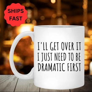 Puede incluir: Taza de café de cerámica blanca con texto negro que dice "Lo superaré, solo necesito ser dramático primero".