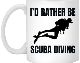 Puede incluir: Taza de café de cerámica blanca con una silueta negra de un buceador y el texto "I'd rather be scuba diving".
