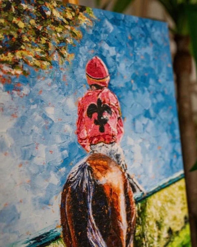 May include: Oil painting of a jockey on a horse, viewed from behind. The jockey wears a red cap and jacket with a black fleur-de-lis. The background features a blue sky and green grass, with a tree in the upper left corner.