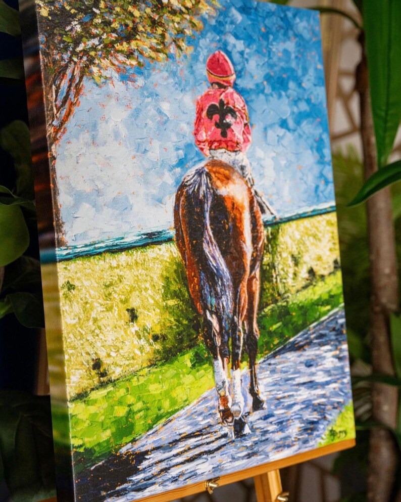 May include: Oil painting on canvas of a jockey on a horse, viewed from behind. The jockey wears a red cap and jacket with a black fleur-de-lis. The horse is brown and white, and the background features a blue sky, green field, and a tree.