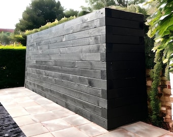 Puede incluir: Una valla o pared de privacidad de madera negra con tablones horizontales. La valla está hecha de madera teñida oscura y está frente a un patio pavimentado.