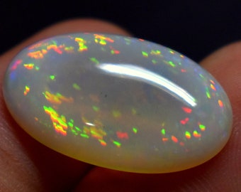 Può includere: Un cabochon di opale bianco con un arcobaleno di colori, tra cui rosso, arancione, giallo, verde, blu e viola.