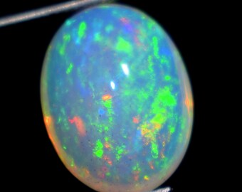 Può includere: Una pietra preziosa di opale bianco con una base blu chiaro e lampi di colore verde, rosso e arancione.