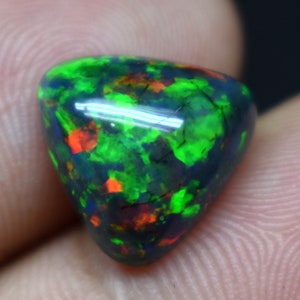 May include: A triangular black opal gemstone with green, red, and blue flashes of color.