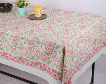 May include: A light green tablecloth with a floral pattern of pink roses and green leaves. The tablecloth has a white border with a red floral design. A wooden tray holds a yellow mug with yellow stripes.