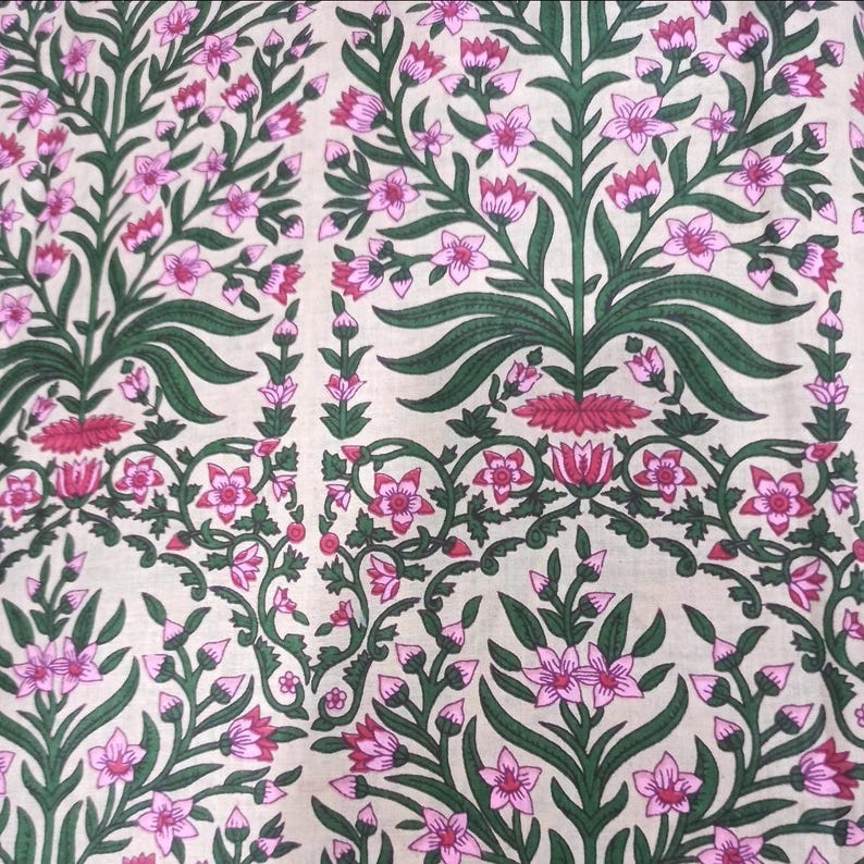 May include: Floral fabric with a repeating pattern of pink flowers, green leaves, and stems on a cream background. The design features stylized floral arrangements and delicate vines, creating a visually appealing textile.