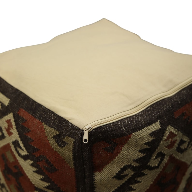 Puede incluir: Un puf cuadrado con una funda de tela beige extra&iacute;ble. La funda tiene una cremallera y el puf est&aacute; cubierto de una tela estampada en marr&oacute;n y rojo.