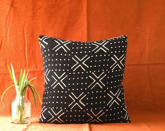 May include: Black and white patterned throw pillow with a geometric design. The pillow is on a solid orange background.