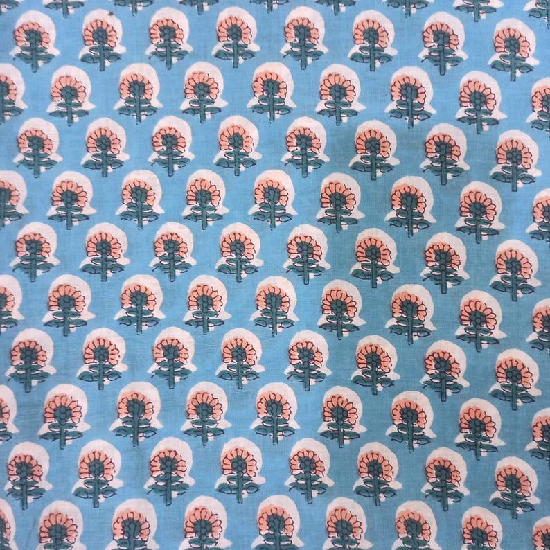 Peut inclure: Un tissu bleu clair avec un motif floral r&eacute;p&eacute;titif. Chaque fleur a un centre p&ecirc;che, des p&eacute;tales blancs et des tiges et feuilles vertes. Le motif est uniform&eacute;ment r&eacute;parti sur le tissu.