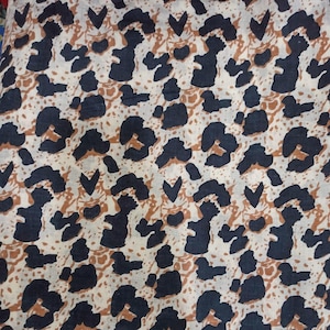Peut inclure: Gros plan sur un tissu avec un motif animalier r&eacute;p&eacute;titif. Le motif pr&eacute;sente des formes bleu marine fonc&eacute; et marron sur un fond cr&egrave;me. Le motif rappelle un imprim&eacute; l&eacute;opard ou gu&eacute;pard.