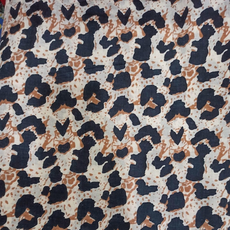 Peut inclure: Gros plan sur un tissu avec un motif animalier r&eacute;p&eacute;titif. Le motif pr&eacute;sente des formes bleu marine fonc&eacute; et marron sur un fond cr&egrave;me. Le motif rappelle un imprim&eacute; l&eacute;opard ou gu&eacute;pard.
