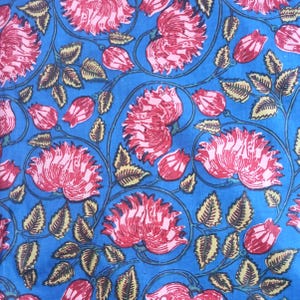 Peut inclure: Un textile vibrant avec un motif floral r&eacute;p&eacute;titif. De grandes fleurs rouges stylis&eacute;es avec des centres roses et des boutons sont dispos&eacute;es sur un fond bleu vif. Des feuilles et des vignes vertes compl&egrave;tent le motif, cr&eacute;ant une impression vivante et color&eacute;e.