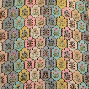 May include: A patterned fabric featuring a repeating design of floral motifs in various colors. The design includes flowers in pink, blue, yellow, and peach, set against a backdrop of gray, teal, and beige. The overall pattern is symmetrical and ornate.