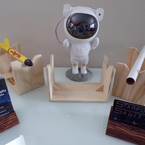 May include: A selection of space-themed items, including a white astronaut figurine, wooden business card holders, and a yellow rocket. Business cards with the text "Starport Sagitta" are displayed.