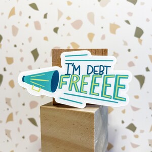 vinyl waterproof sticker that says i'm debt free in white green and yellow perfect for debt free party favors