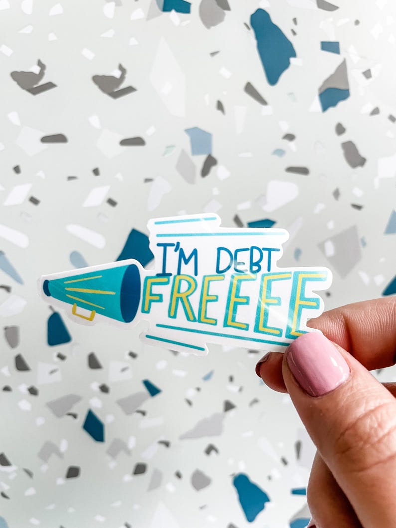 Hand holding sticker that says i'm debt free with a megaphone for money goals and paid off celebrations