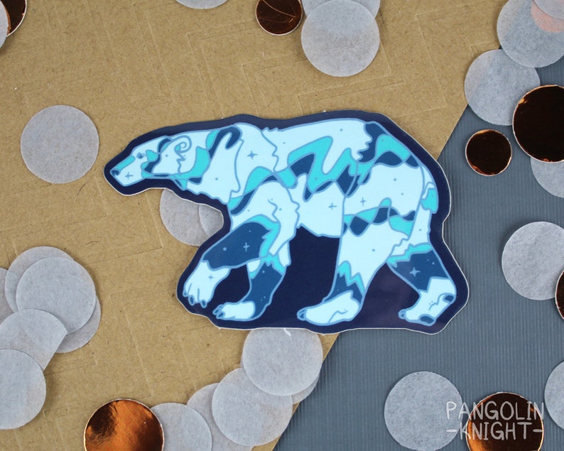 May include: A blue and white polar bear sticker with a starry night sky design. The sticker is on a brown background with white and gold confetti.