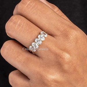 Puede incluir: Un anillo de banda de oro con una fila de piedras preciosas ovaladas transparentes.