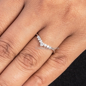 May include: A silver ring with a V-shaped row of small, clear stones.