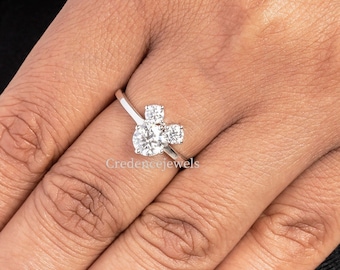 May include: A silver ring featuring a cluster of clear cubic zirconia stones set in a Mickey Mouse head design. The ring is worn on a person's finger.
