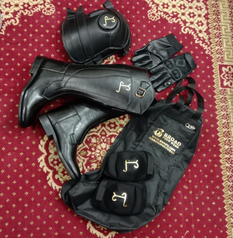 May include: A set of black equestrian gear including tall leather riding boots with gold logos, a pair of black gloves, two black knee guards with gold logos, and a black equipment bag featuring the text Broad Polo Wear and website info.