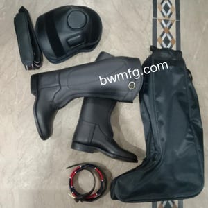 May include: A set of black equestrian gear including a pair of tall riding boots, a helmet, a tall boot storage bag, a strap, and a coiled belt with red and blue stripes. The text "bwmfg.com" is visible across the center of the riding boots.