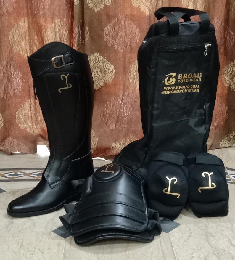 May include: A black tall riding boot with a buckle strap, a black protective knee guard, two black padded knee pads, and a black equipment bag. The bag features the gold text BROAD POLO WEAR, WWW.BWMFG.COM, and @BROADPOLOWEAR. All items feature a gold logo.