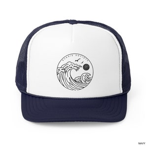Pu&ograve; includere: Cappellino da camionista blu navy e bianco con una grafica nera di onde oceaniche, un sole e uccelli all'interno di un cerchio. Il testo "SUNNIE SOCIETY" &egrave; sopra la grafica. Il cappellino ha un retro in rete e una visiera curva.