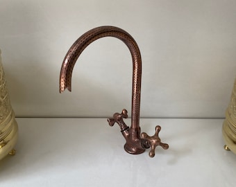 May include: A copper kitchen tap with a hammered finish and two cross-shaped handles.