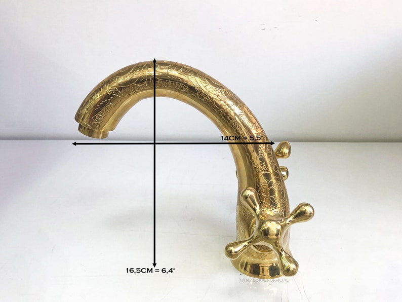 Op de afbeelding: Gouden kraan met een sierlijk ontwerp. De kraan is 14 cm breed en 16,5 cm hoog.