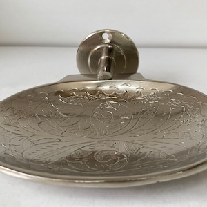 Pu&ograve; includere: Portasapone da parete in argento con un design floreale decorato.