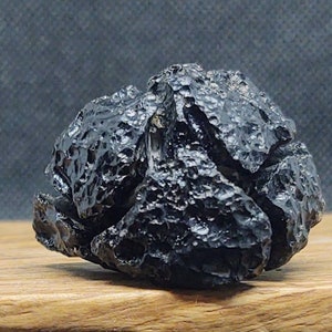 May include: A black, irregularly shaped rock with a rough, textured surface. The rock has a dark, almost metallic sheen.