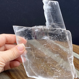 Puede incluir: Un gran cristal de selenita transparente con una estructura única en capas. El cristal es translúcido y tiene una superficie lisa y pulida.