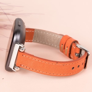 May include: A brown leather watch strap with silver fittings and a black watch face.