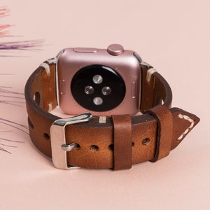 Stainless steel buckle and adapter detail on handmade leather Apple Watch band.