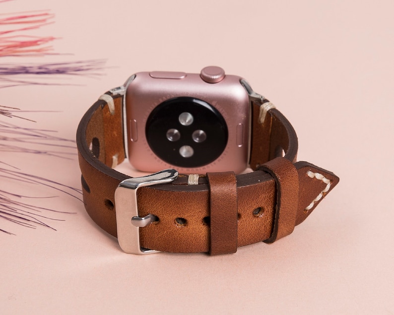 Stainless steel buckle and adapter detail on handmade leather Apple Watch band.