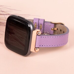 May include: A purple leather watch band with rose gold accents and a black smartwatch face.