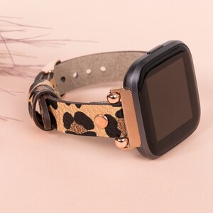 May include: A black smartwatch with a rose gold band and a leopard print leather strap. The watch face is black and the band has gold accents.