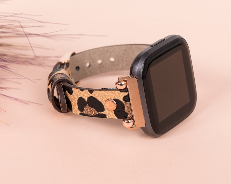 May include: A black smartwatch with a rose gold band and a leopard print leather strap. The watch face is black and the band has gold accents.