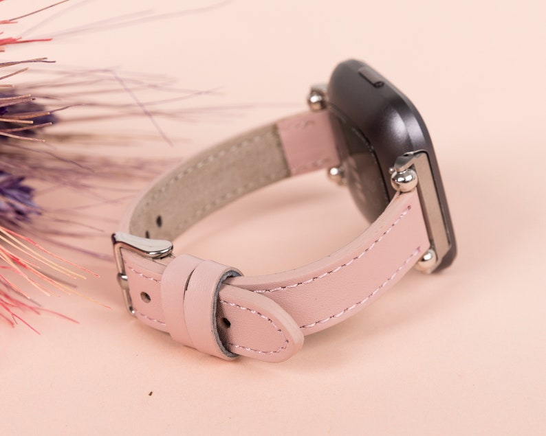 May include: A pink leather watch band with silver hardware and a black watch face.