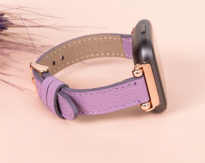 K&ouml;nnte beinhalten: Ein violettes Lederarmband mit ros&eacute;goldenen Akzenten und einem schwarzen Zifferblatt.