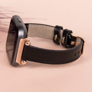 May include: A black leather watch strap with rose gold accents and a square-shaped watch face.