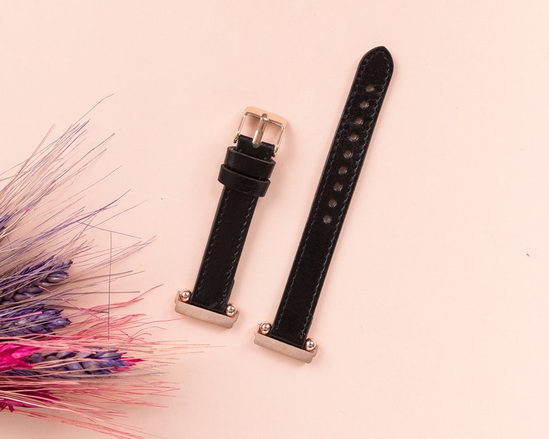 May include: Two black leather watch straps with gold accents. The straps have multiple holes for adjusting the size.