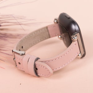 May include: A pink leather watch band with silver hardware and a black watch face.