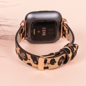 May include: A brown and black leopard print watch band with a rose gold buckle and a black smartwatch face.