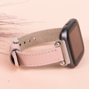 May include: A pink leather watch band with silver accents and a black smartwatch face.