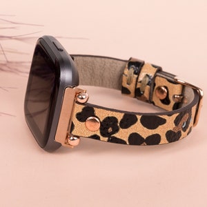 May include: A black smartwatch with a rose gold band featuring a leopard print pattern.