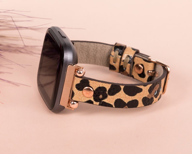 May include: A black smartwatch with a rose gold band featuring a leopard print pattern.