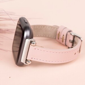 May include: A pink leather watch band with silver accents and a black smartwatch face.