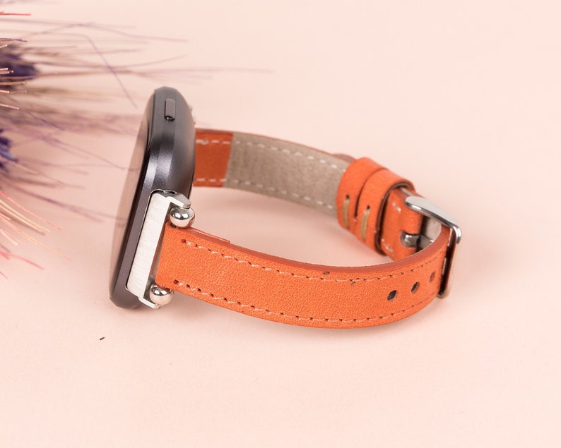 May include: A brown leather watch strap with silver fittings and a black watch face.